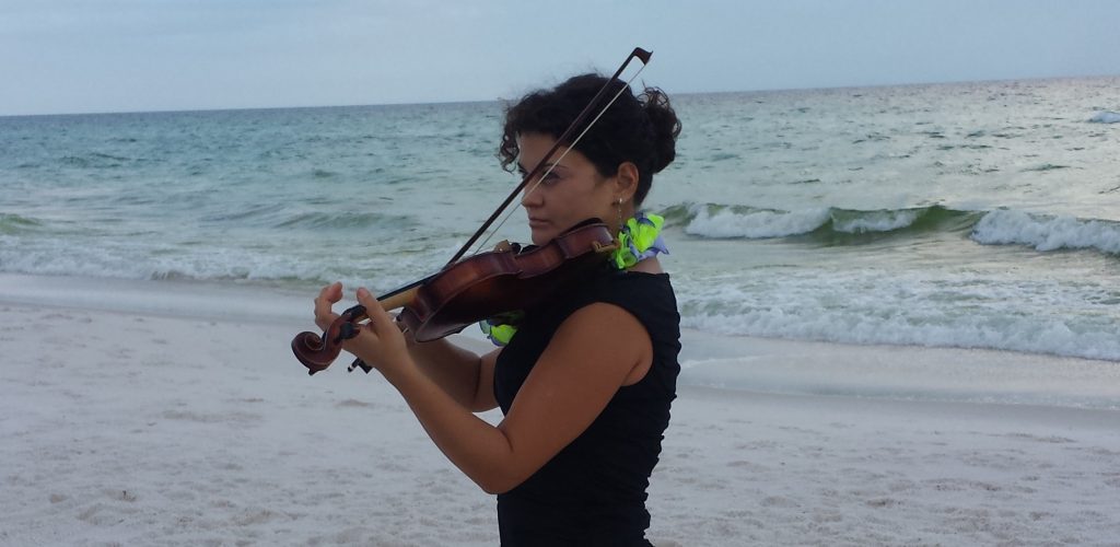 A woman playing the violin on the beach